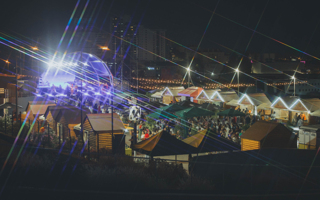 Vista noturna do recinto do Amadora Beer Fest 2026 com palco e bares