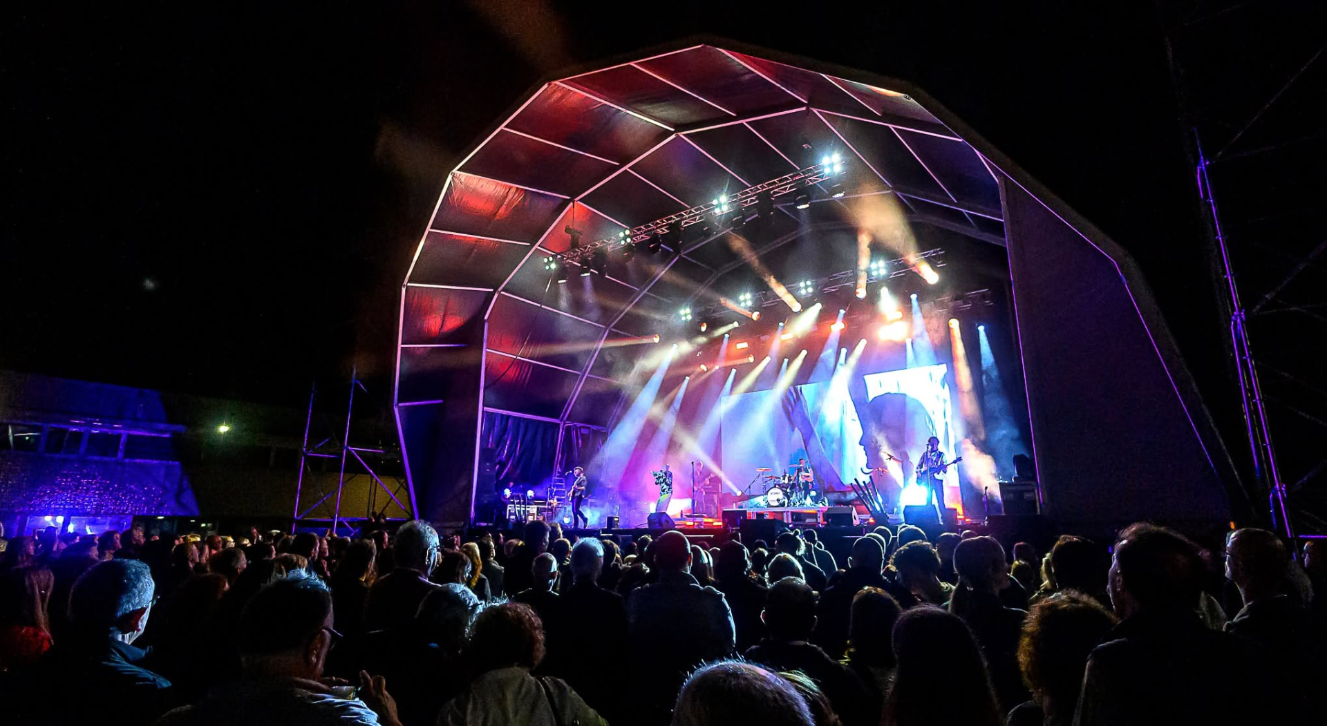 Palco de festival ao vivo com iluminação laranja e multidão